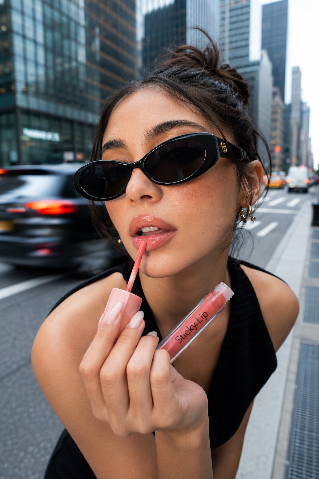Creator applying lip color while holding the product on a city street
